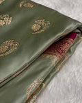 Green fabric with gold embroidery on a textured white background
