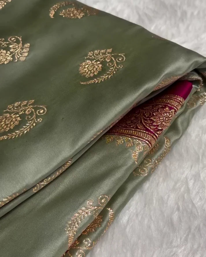 Green fabric with gold embroidery on a textured white background